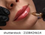 Small photo of Young woman undergoing procedure of permanent lip makeup in tattoo salon, top view