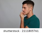 Man biting his nails on grey background, space for text. Bad habit
