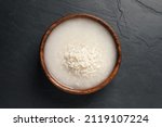 Small photo of Rice soaked in water on black table, top view