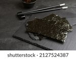 Small photo of Dry nori sheets and chopsticks on black table