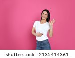 Happy woman touching her belly and showing okay gesture on pink background, space for text. Concept of healthy stomach