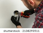 Electrician with pliers repairing power socket, closeup