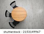 Stylish round table with black chairs on floor, top view. Space for text