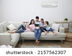 Happy family resting under air conditioner on white wall at home