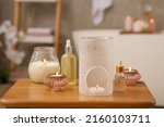 Aroma lamp, bottles of oils and candles on wooden table in bathroom