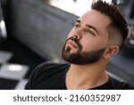 Handsome young man with fresh haircut and groomed beard in barbershop
