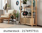 Living room interior with stylish turntable on wooden shelving unit and vinyl records