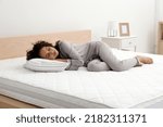 Young African American woman sleeping on bed with comfortable mattress and pillow at home