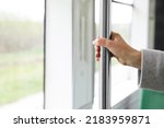 Woman holding grab pole near window in public transport, closeup. Space for text