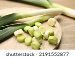 Whole and cut fresh leeks on wooden table, closeup