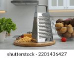 Grater, cheese and vegetables on table in kitchen