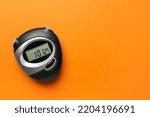Digital timer on orange background, top view. Space for text