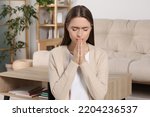 Small photo of Woman with clasped hands praying at home