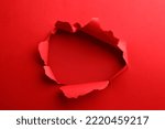 Hole in red paper on color background