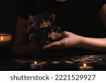 Small photo of Soothsayer shuffling tarot cards at table in darkness. Fortune telling