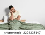 Sleep deprived man sitting on bed at home. Space for text