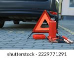 Small photo of Emergency warning triangle and safety equipment near car, space for text