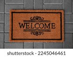 Small photo of Doormat with word Welcome on pavement, top view