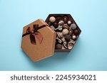 Box of delicious chocolate candies on light blue background, top view