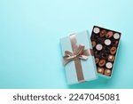 Open box of delicious chocolate candies on light blue background, flat lay. Space for text