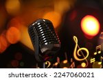 Retro microphone, music notes and other musical symbols against festive lights, closeup