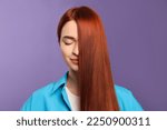 Beautiful woman with red dyed hair on purple background
