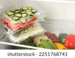 Vacuum bags with different vegetables in fridge, space for text. Food storage