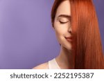 Beautiful woman with red dyed hair on purple background, space for text