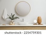Stylish mirror, eucalyptus branches and vessel sink in modern bathroom. Interior design
