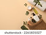 Preparation for spa. Compact toiletry bag with different cosmetic products, sea salt and towel on beige background, flat lay. Space for text