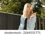 Small photo of Woman smoking cigarette near railing outdoors. Space for text