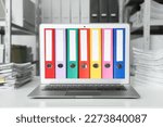 Store and organize information. Modern laptop with hardcover office folders on screen in archive room