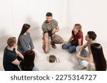Small photo of Soldier in military uniform teaching group of people how to apply medical tourniquet indoors
