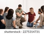 Small photo of Soldier in military uniform teaching group of people how to apply medical tourniquet indoors