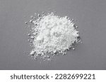 Small photo of Heap of calcium carbonate powder on grey table, top view