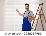 Small photo of Worker in uniform and stepladder near horizontal window blinds indoors