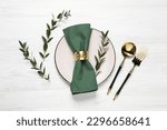 Stylish setting with cutlery and eucalyptus leaves on white wooden table, flat lay