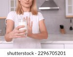 Small photo of Woman with glass of milk suffering from lactose intolerance in kitchen, closeup. Space for text