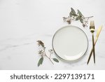 Stylish setting with cutlery and eucalyptus leaves on white marble table, flat lay. Space for text
