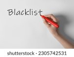 Small photo of Woman writing word Blacklist on whiteboard, closeup