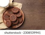 Tasty chocolate sandwich cookies with cream on wooden table, top view. Space for text