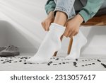 Woman putting on white socks at ...
