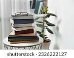 Stack of many different books and glasses on coffee table indoors. Space for text