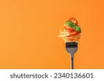 Tasty pasta with tomato sauce and basil on fork against orange background, space for text