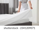 Small photo of Maid making bed in hotel room, closeup