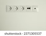 Small photo of Many power sockets with ethernet and TV coax plates on white wall indoors. Space for text