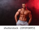 Young bodybuilder with muscular body in smoke on color background, space for text