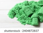 Small photo of Castle figures made of green kinetic sand on white table, closeup