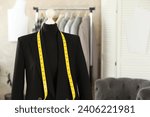 Mannequin with black jacket and measuring tape in tailor shop, space for text