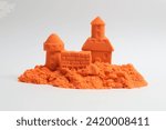 Small photo of Castle figures made of orange kinetic sand isolated on white